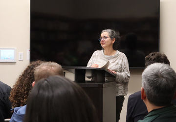 Dr. Cintia Santana reads from her collection of poetry to audience members in the German Library at Stanford University.